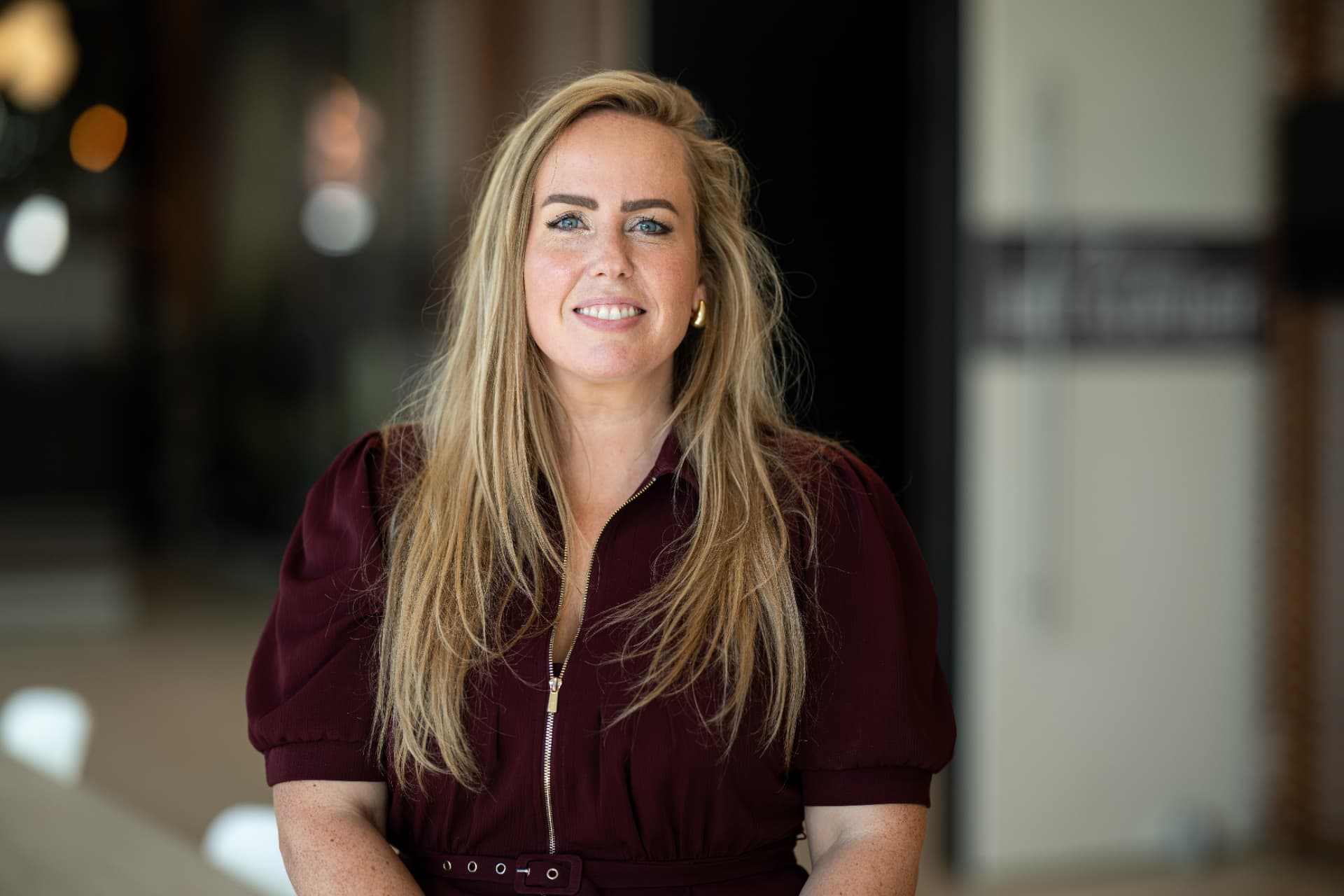 Sabine van der Hulst glimlachend in een bordeauxrode jurk